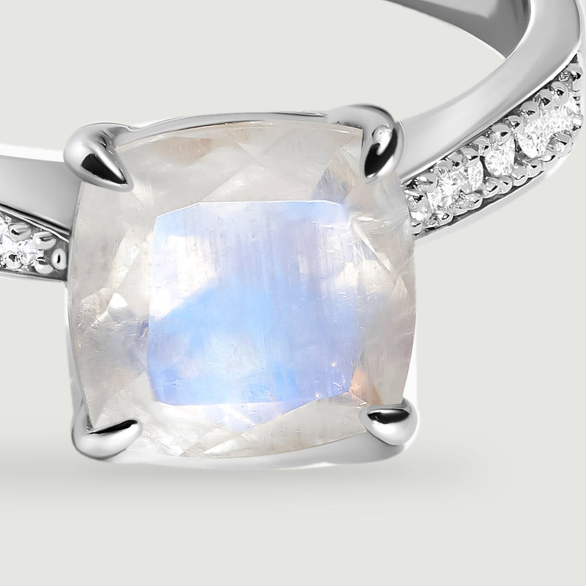 A close view of the white gold ring highlights the pale moonstone facets and round diamonds along its shoulders.