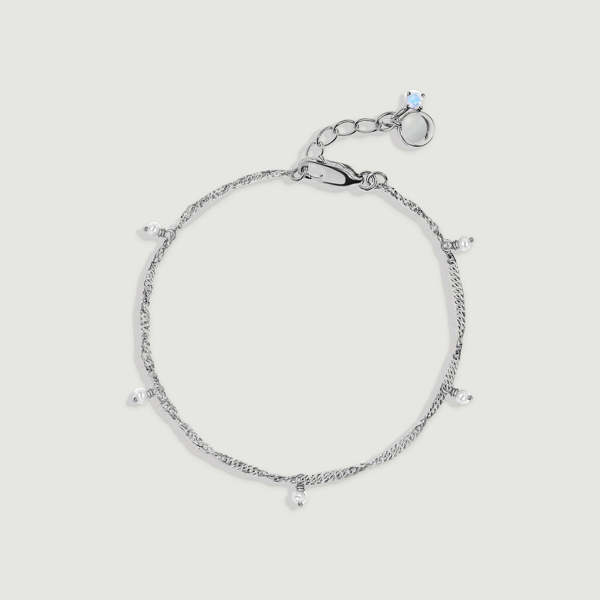 A silver anklet forms an oval with five dangling pearls and a lobster clasp on light gray.