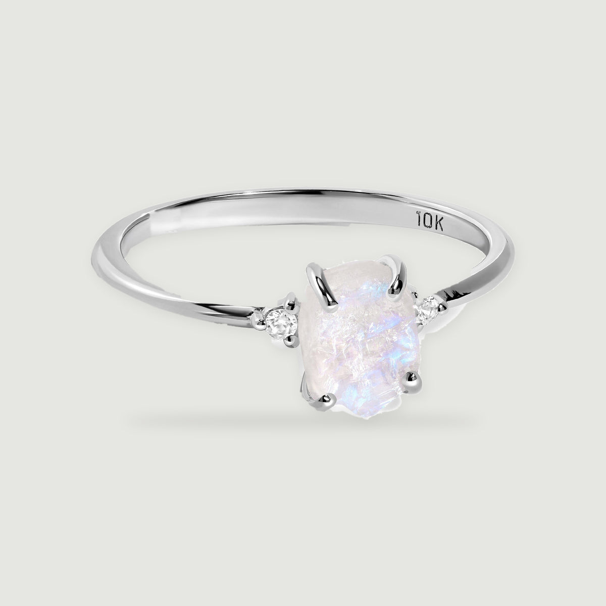 A white gold ring shows a translucent moonstone with blue reflections and four curved prongs.