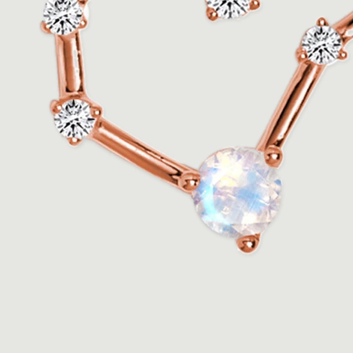 A large faceted moonstone sits between polished rose gold bars and small round diamond settings.