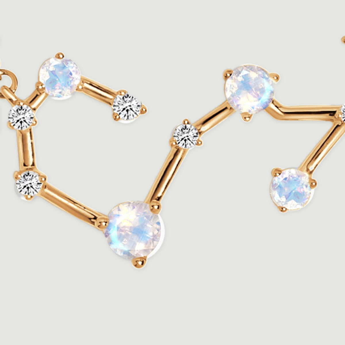 A close view of the yellow gold pendant shows round luminous stones linked by curved polished bars.