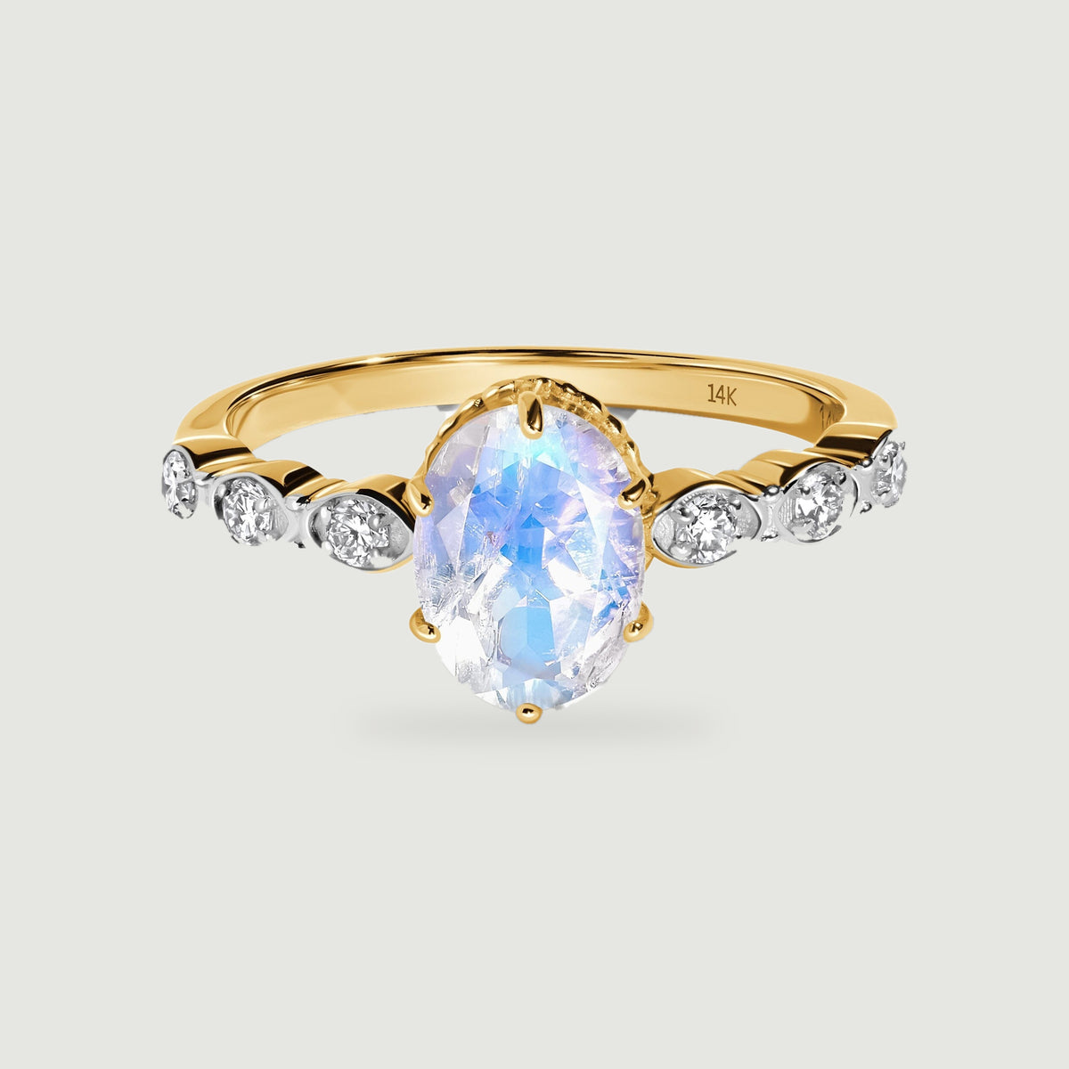 A yellow gold band holds an oval moonstone above six bright round diamond accents.