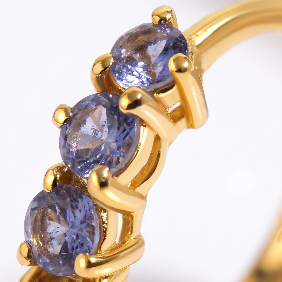 Violet stones sit between rounded yellow gold-tone prongs in a close view of the hoop.