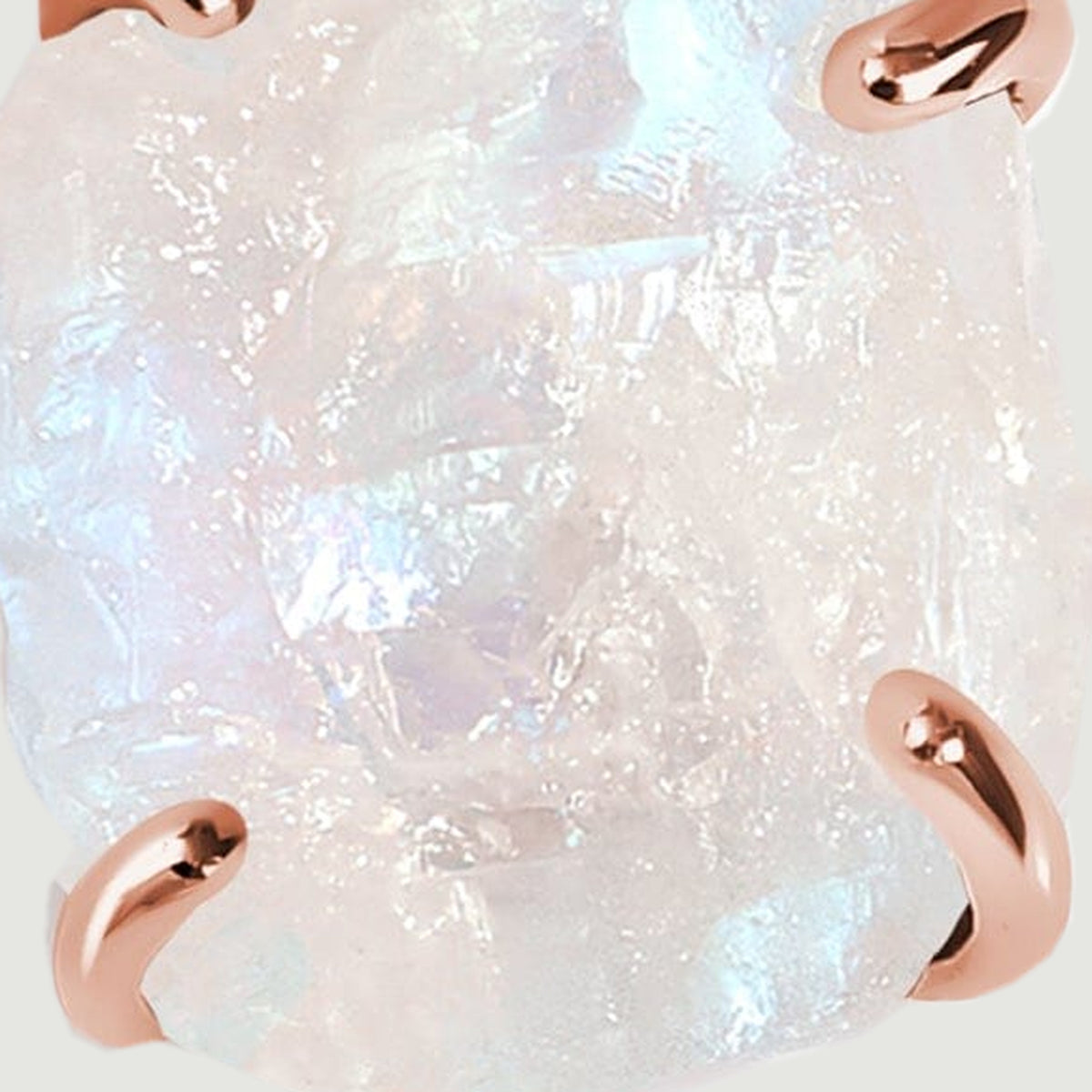 Blue and pearly flashes appear across the uneven surface of the moonstone between rose gold prongs.