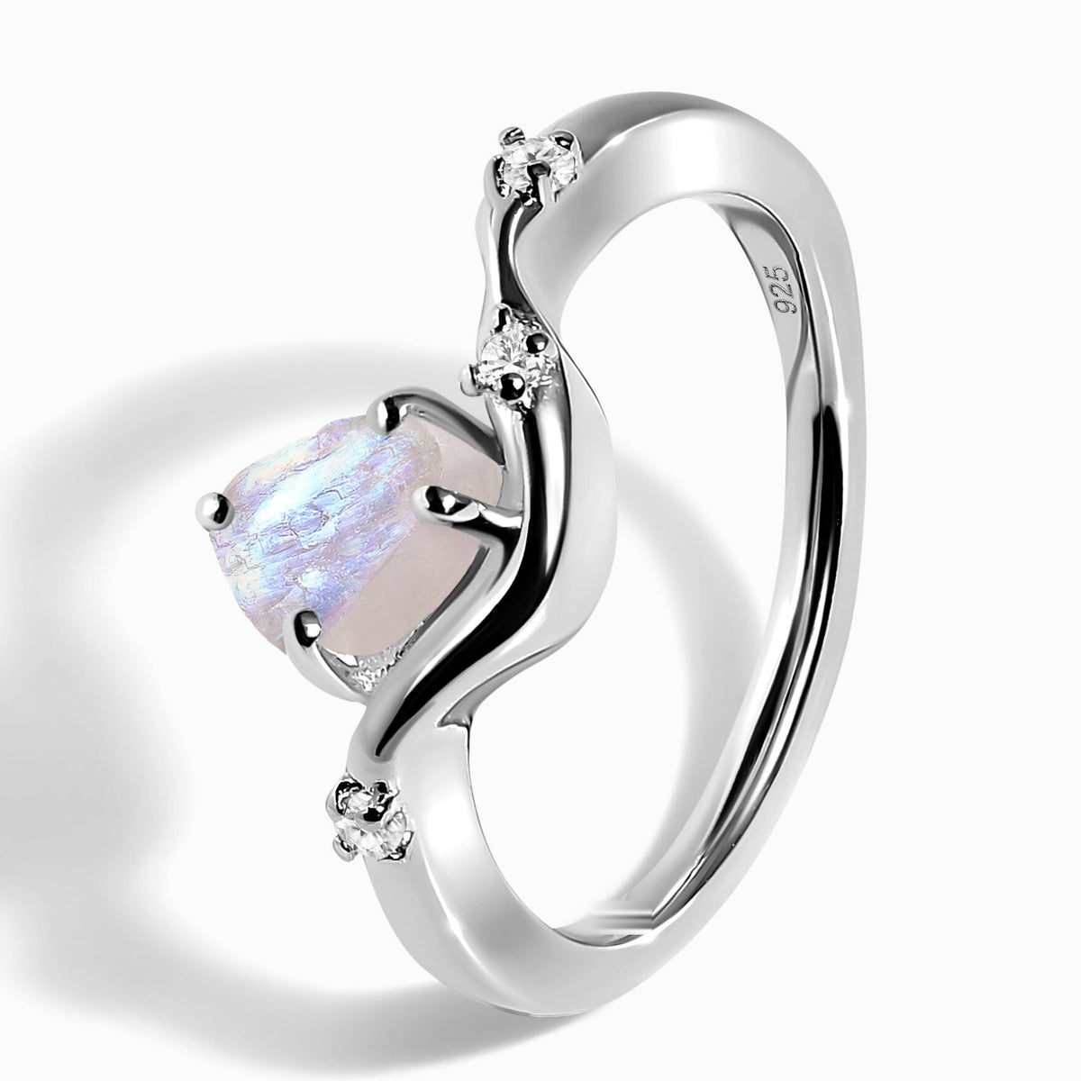 The sterling silver ring rests at an angle on a light tabletop, showing its raised moonstone, curved band, and 925 stamp.