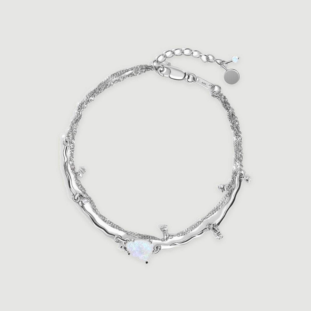 A sterling silver bracelet forms an oval with an irregular pale moonstone, a double chain and a lobster clasp on a light gray surface.