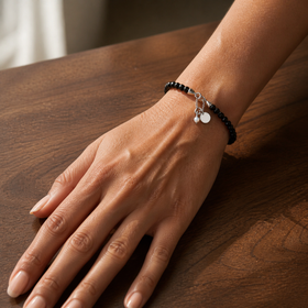 Night Shield black obsidian bracelet worn on a wrist over a warm walnut table