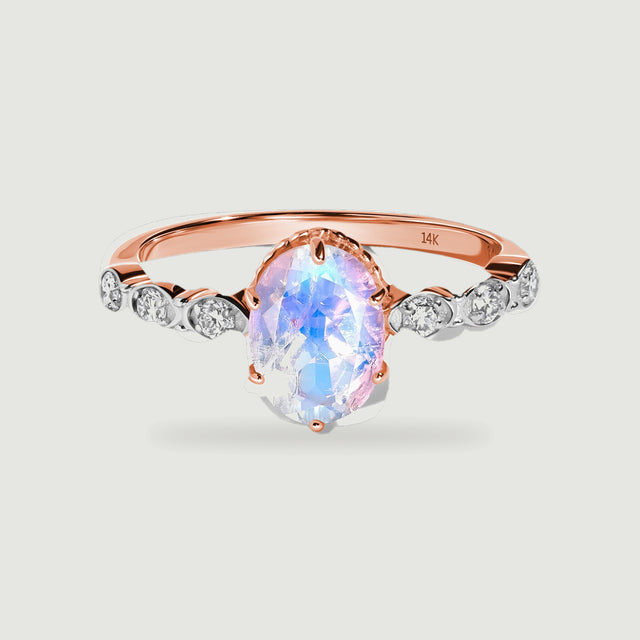 A rose gold ring displays a faceted oval moonstone held by prongs and a row of round diamond accents.