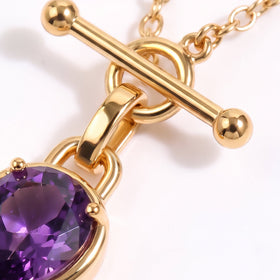 Close macro of a bar clasp, circular connector, chain links, and faceted purple gemstone.