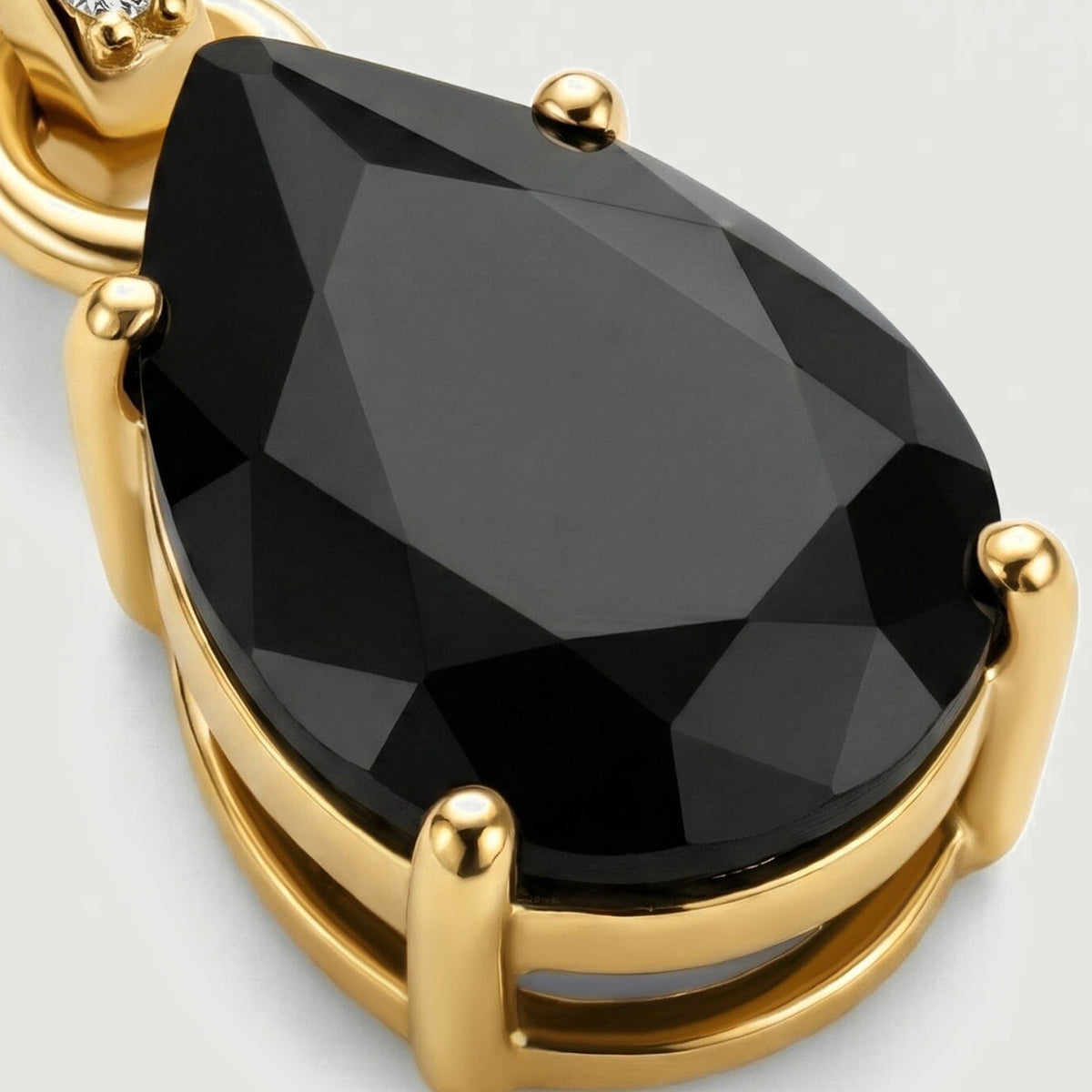 An angled detail reveals the raised gold prongs and open gallery underneath the faceted black onyx stone.