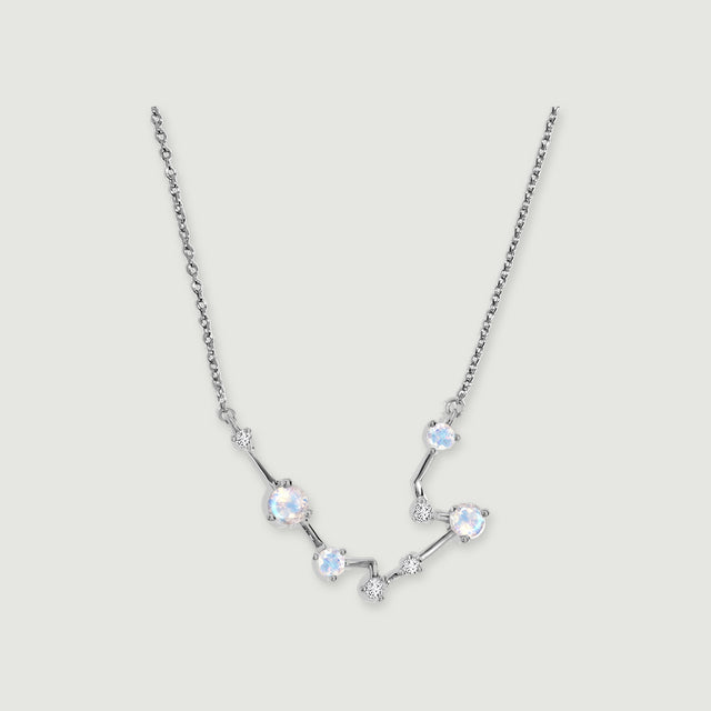 A silver chain frames a curved constellation of four round moonstones and small clear stones on a light gray background.