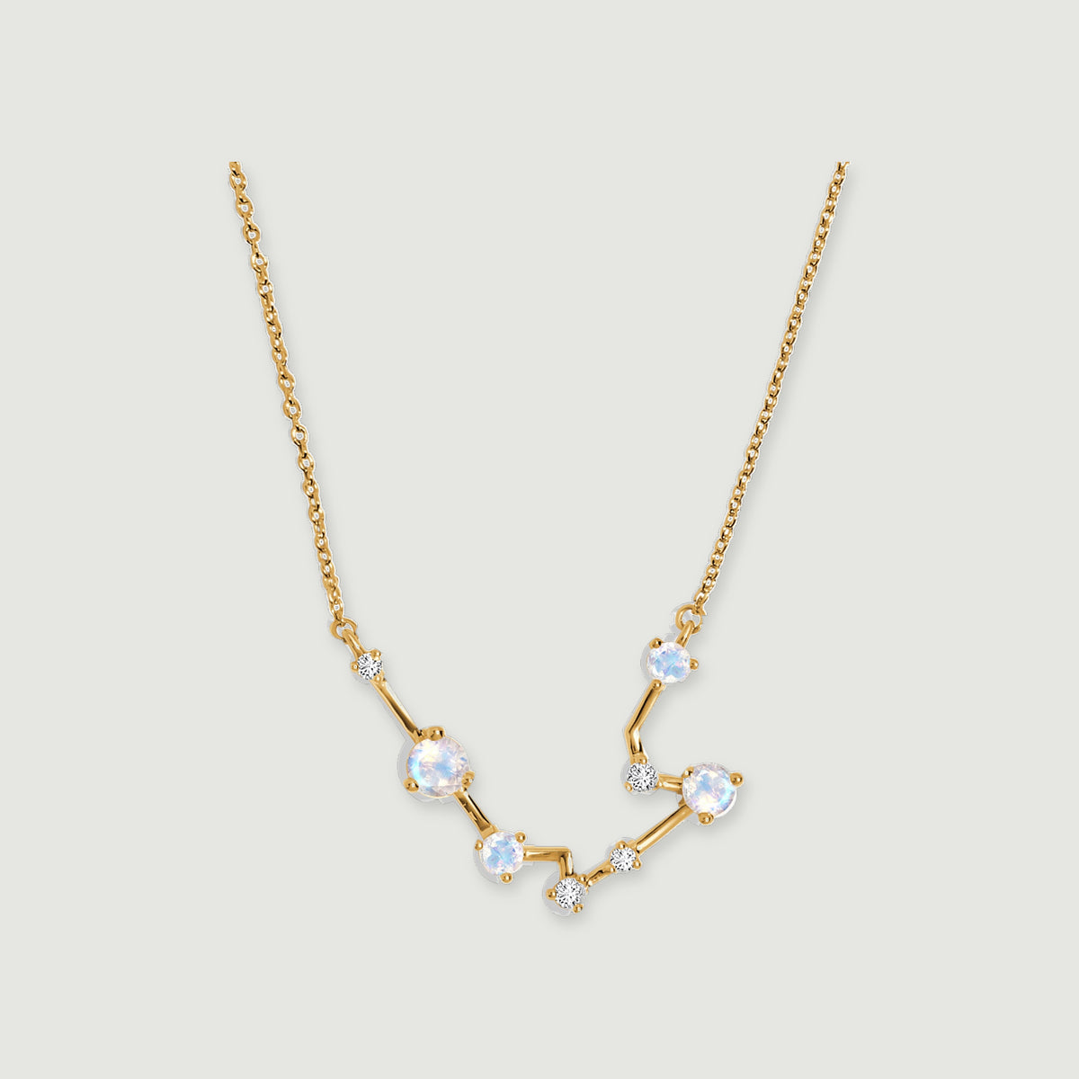 A yellow gold chain meets an angular pendant with pale iridescent stones and clear accents on light gray.