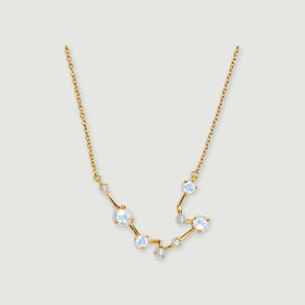 A yellow gold chain meets an angular pendant with pale iridescent stones and clear accents on light gray.