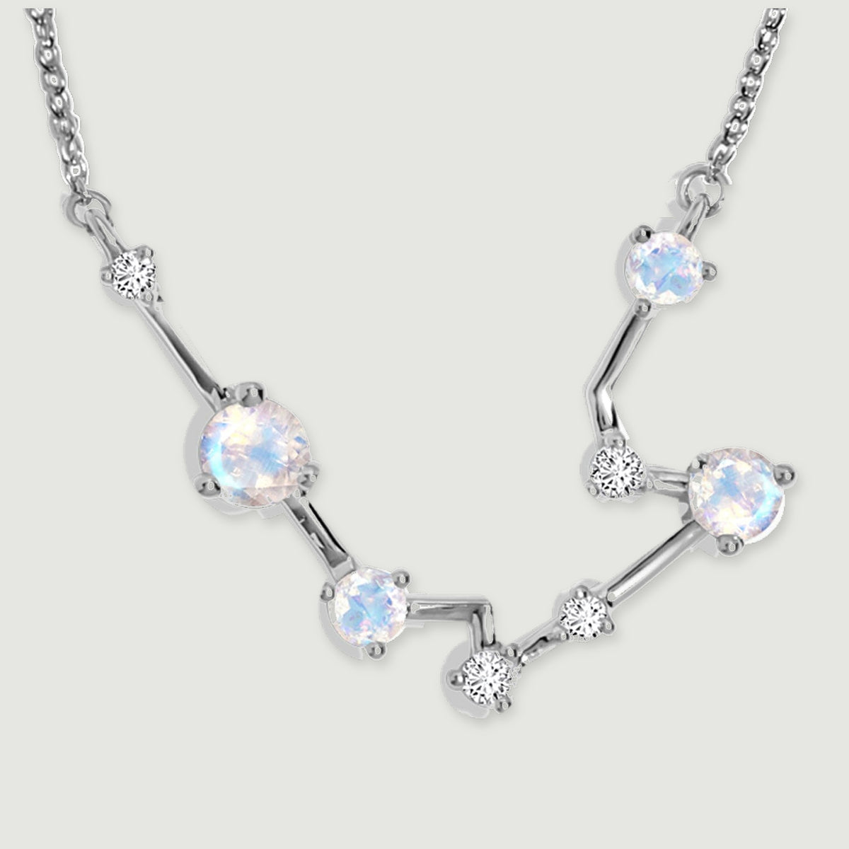Four pale moonstones sit along polished silver bars in a close view of the constellation pendant.