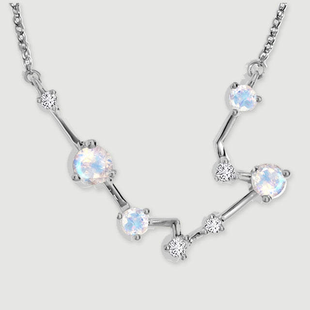 Four pale moonstones sit along polished silver bars in a close view of the constellation pendant.