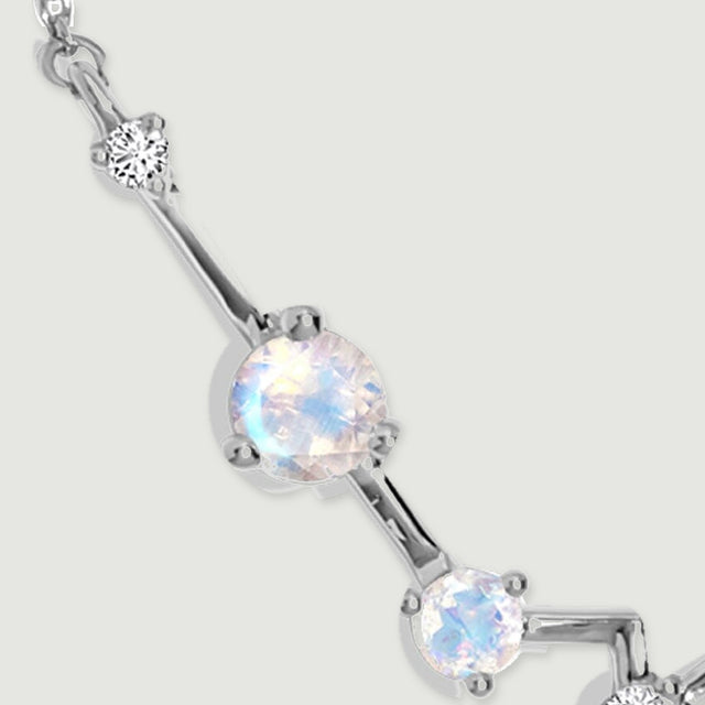 A large pale moonstone and a small clear stone are connected by a polished silver bar.