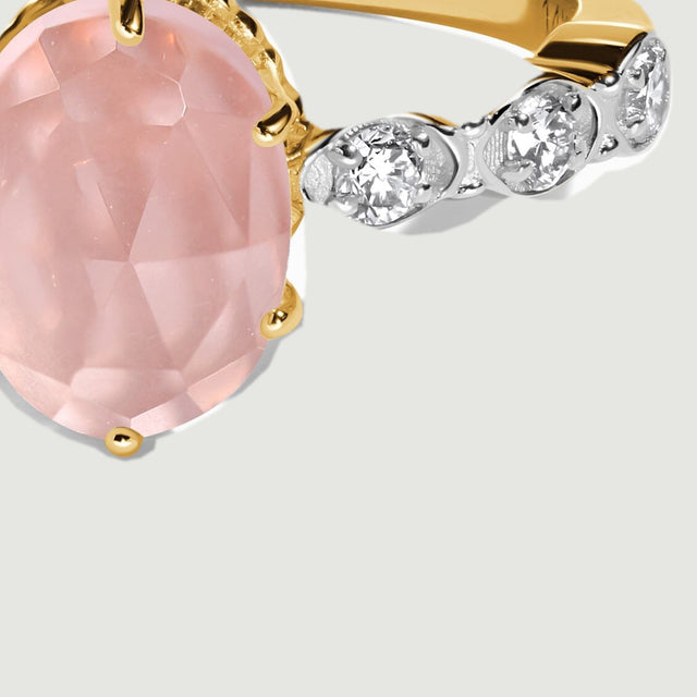 The oval pink stone and bright diamond settings fill a close view of the yellow gold ring front.