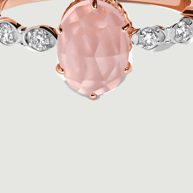 An enlarged view reveals rose gold prongs around the faceted pink stone and the contrasting diamond settings beside it.