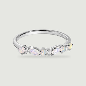 A polished silver ring displays pastel opals and elongated pale stones above a softly shadowed grey surface.