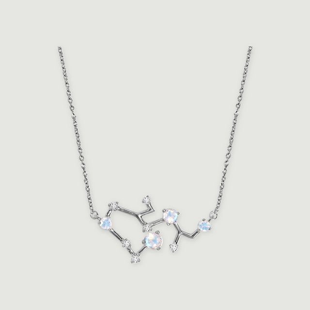 A silver necklace has four iridescent round stones and small clear stones along an angular pendant on a light gray background.