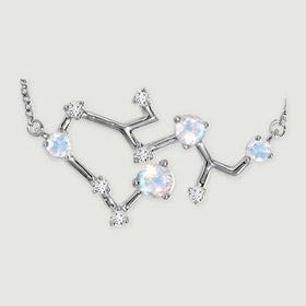 The silver pendant is shown close up with reflective connecting bars, four pale iridescent stones, and clear round accents.