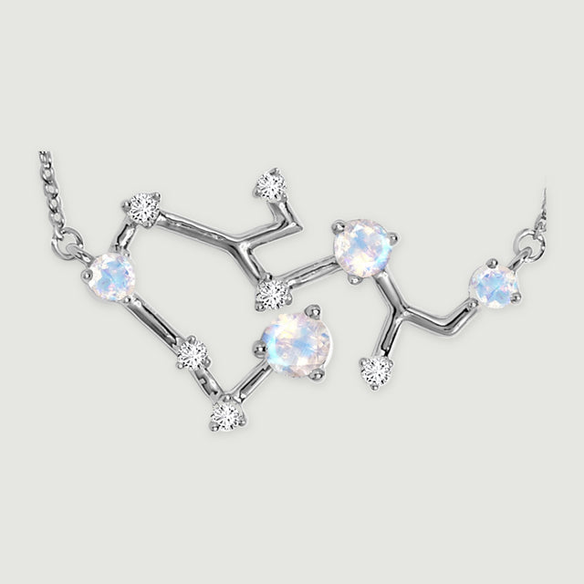 The silver pendant is shown close up with reflective connecting bars, four pale iridescent stones, and clear round accents.