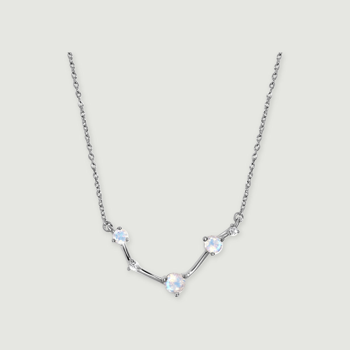 A silver necklace with an angular stone-set centre and a fine link chain is centred on a light grey background.