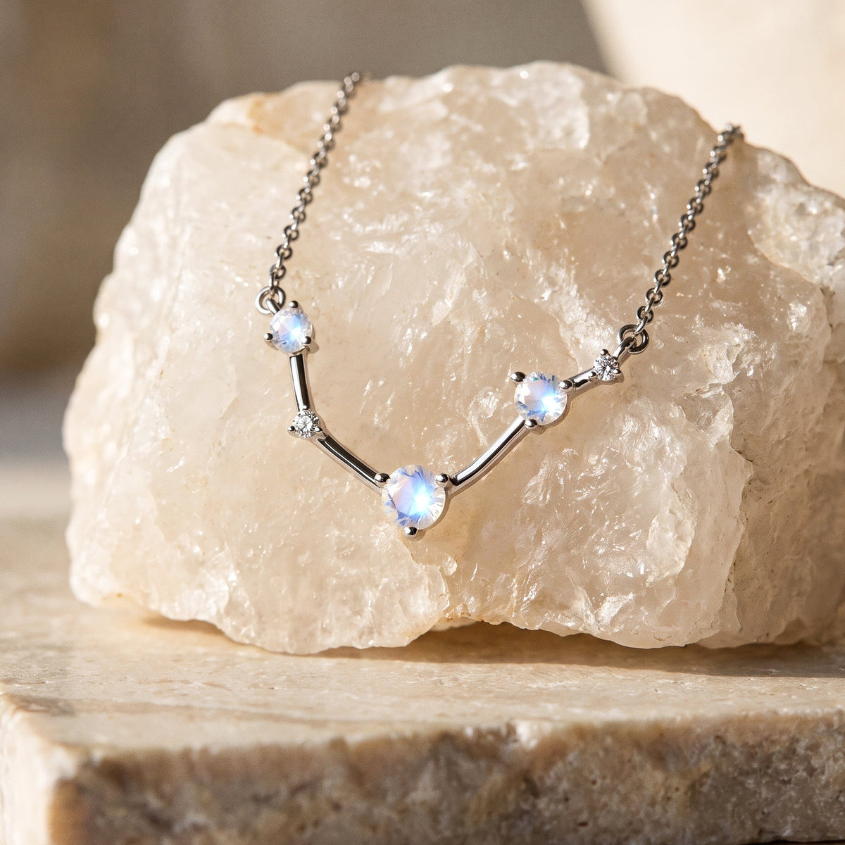 The silver necklace lies across a pale crystal with its round stones and curved centre visible.
