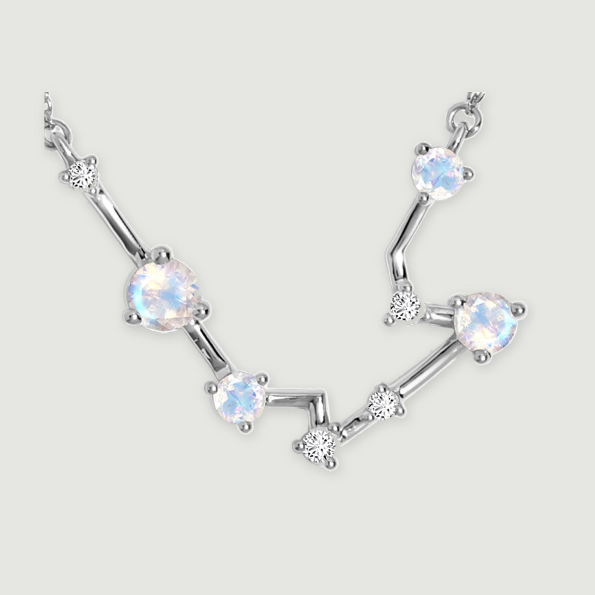 A close view reveals silver prongs around the round moonstones and the smaller clear stones along the angular links.