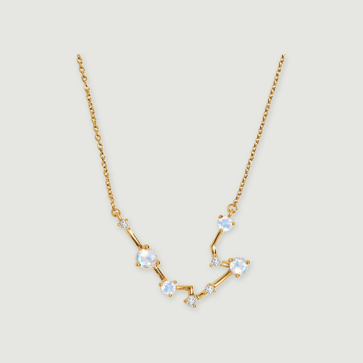 A yellow gold necklace shows polished angular links and round moonstones against a soft gray background.