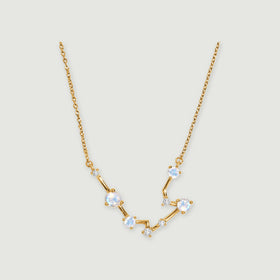 A yellow gold necklace shows polished angular links and round moonstones against a soft gray background.