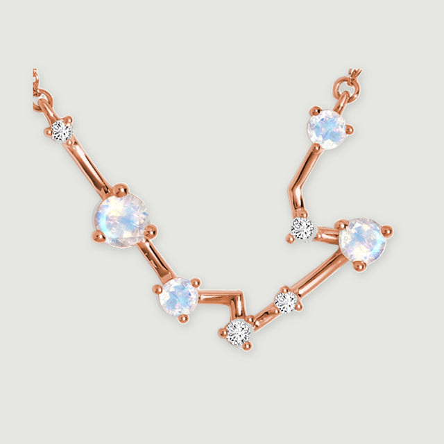 A close view highlights rose gold connecting bars and rounded prongs beside blue white moonstones.