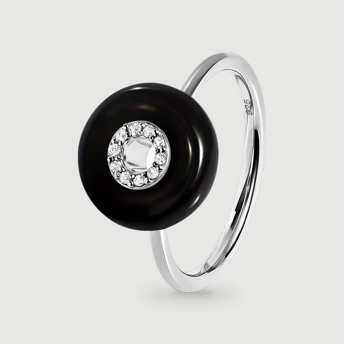 A sterling silver ring with a polished black disc and a circle of clear stones is shown upright against light gray.