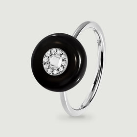 A sterling silver ring with a polished black disc and a circle of clear stones is shown upright against light gray.