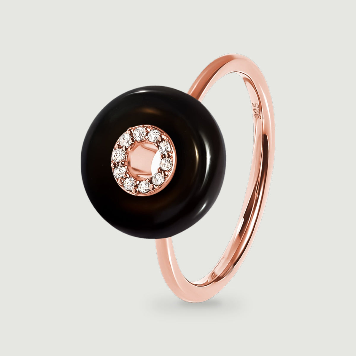 A rose gold vermeil ring features a glossy black round stone and a clear stone halo above its slim band.