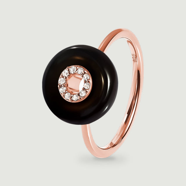 A rose gold vermeil ring features a glossy black round stone and a clear stone halo above its slim band.