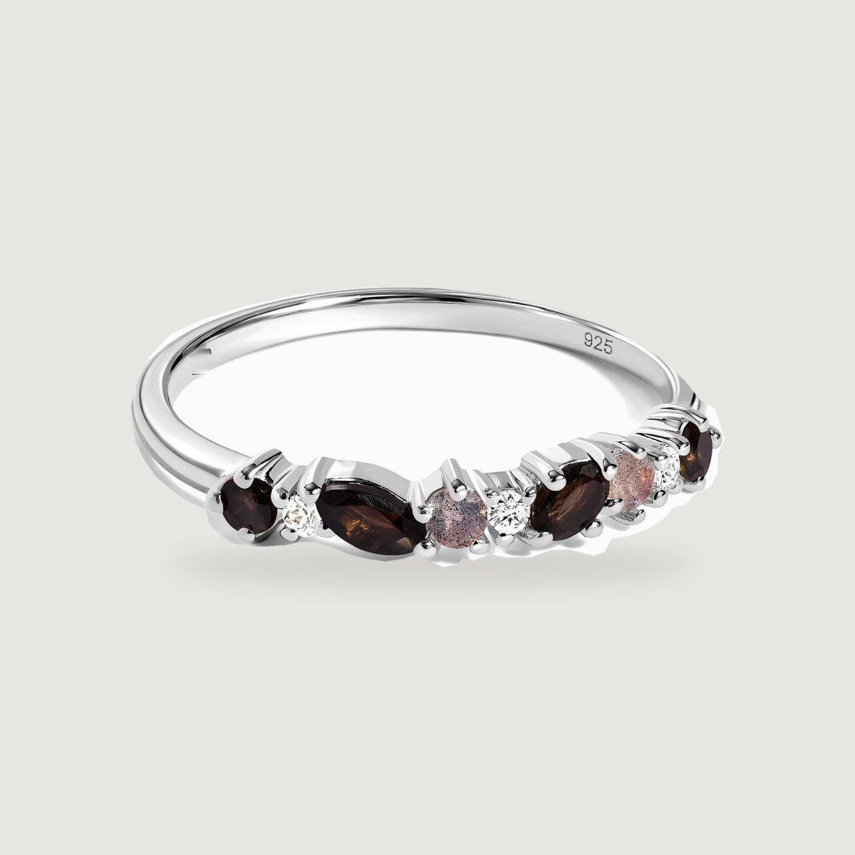 A sterling silver ring with dark faceted stones and clear round accents rests on a light gray background.