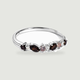 A sterling silver ring with dark faceted stones and clear round accents rests on a light gray background.