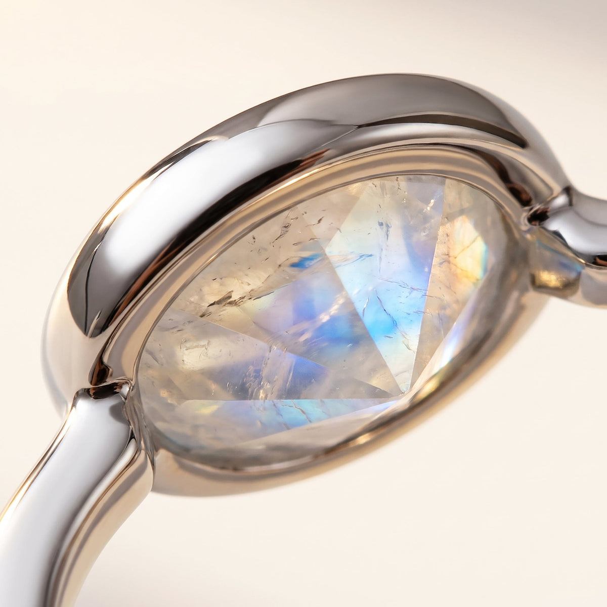 A close view reveals pale blue flashes and natural inclusions within an oval moonstone held by a polished silver bezel.