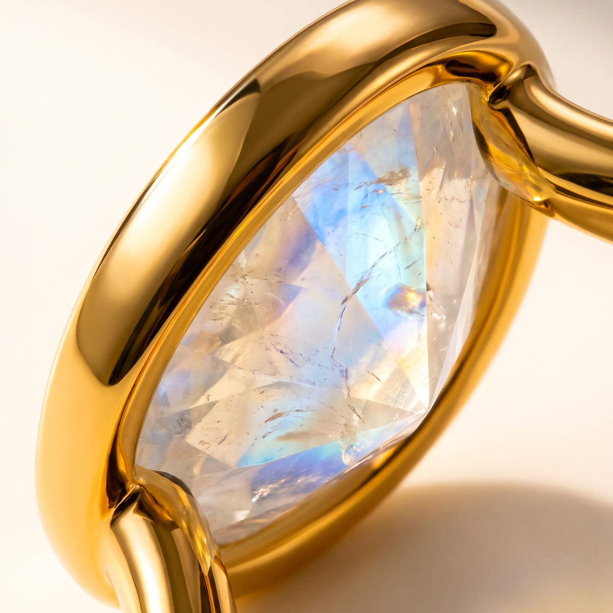 An angled macro view shows the moonstone facets, warm gold bezel, and curved band junction.