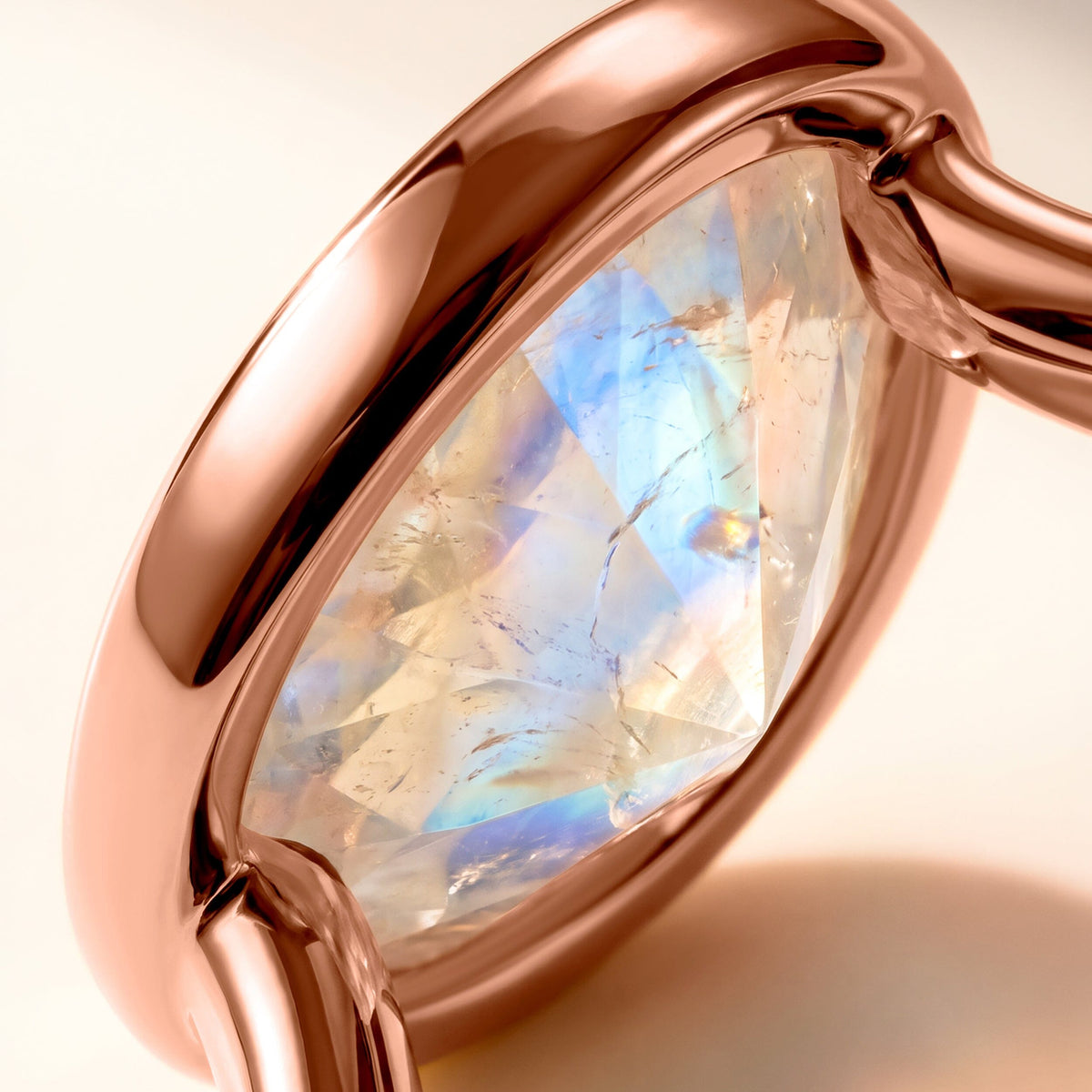 A detailed view fills the frame with a translucent oval moonstone and its smooth rose gold setting.