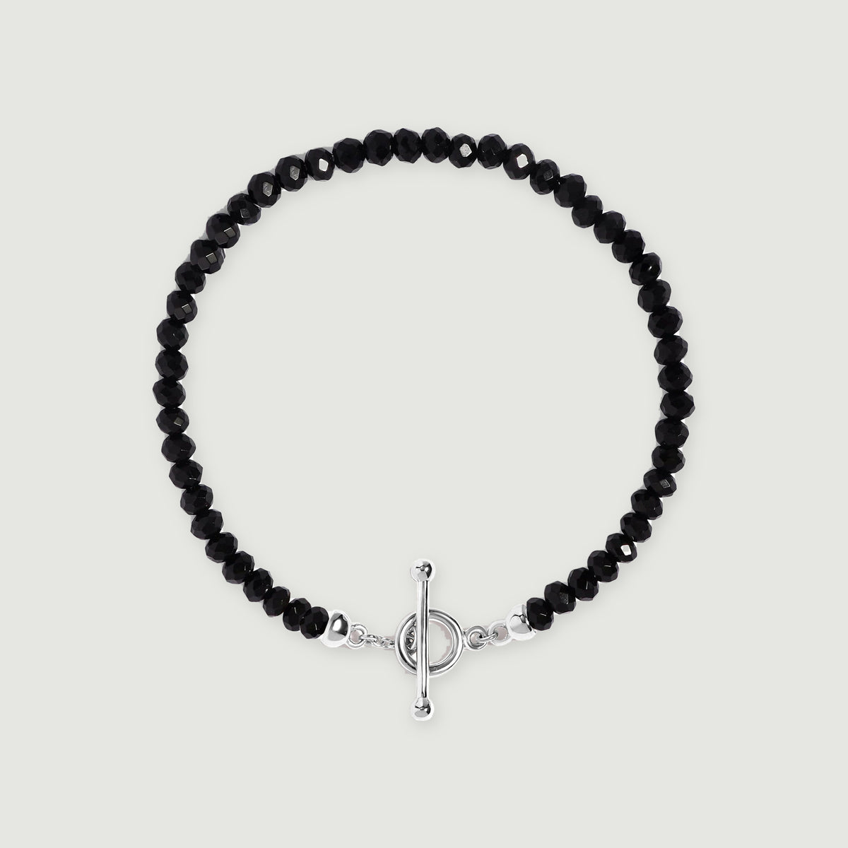 Faceted black obsidian beads form an oval bracelet with a polished silver ring and bar clasp on a light gray background.