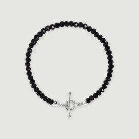 Faceted black obsidian beads form an oval bracelet with a polished silver ring and bar clasp on a light gray background.