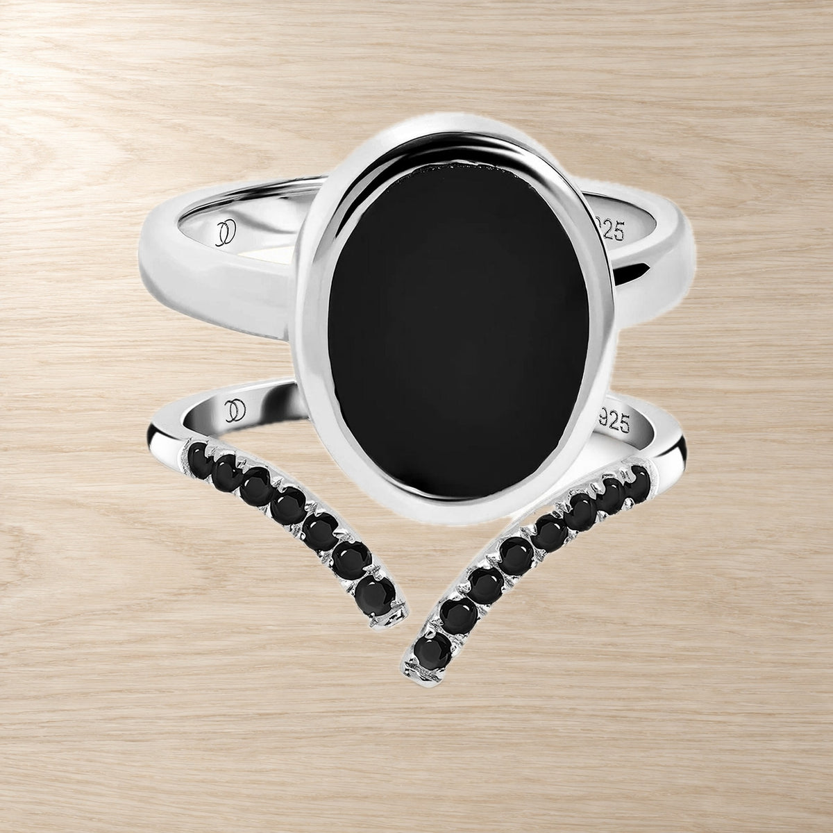 Oval black onyx ring and black spinel band set on a wooden surface