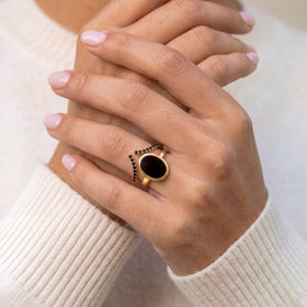Hand wearing the black onyx ring with a black spinel band against a white sleeve