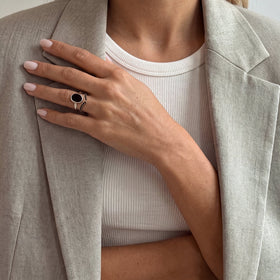 Hand wearing the black onyx ring near a grey jacket