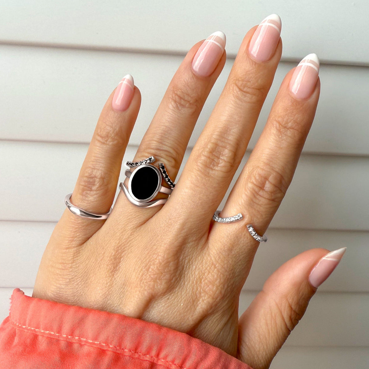 Hand wearing the black onyx ring on a coral sleeve
