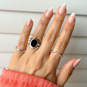 Hand wearing the black onyx ring on a coral sleeve