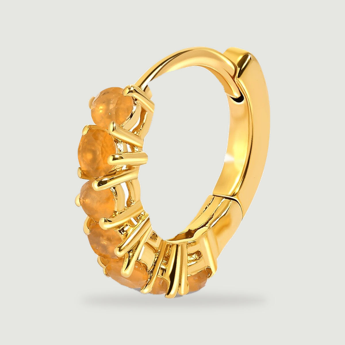 An upright yellow gold plated carnelian hoop reveals its curved back and hinged fastening on light gray.