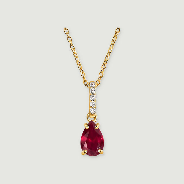 A pear-shaped red ruby hangs beneath a five-stone bail on a yellow gold chain against a light gray background.